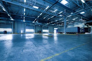 Wide view of an empty modern warehouse with industrial lighting and trucks.